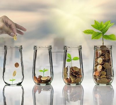 Hand putting Gold coins and seed in clear bottle on cityscape photo blurred cityscape background,Business investment growth concept